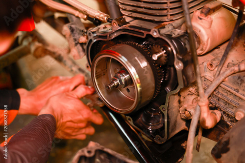 Fotografie Motorcycle engine repair mechanic hand metal gear maintenance close up workshop