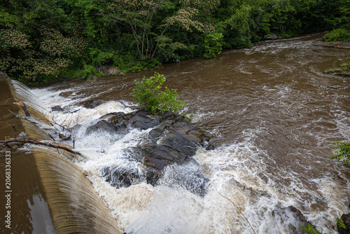 Schilderij op canvas Greenish water flowing over rocks of a dam
