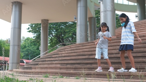 Obraz na plátně Active Asian female students discussing classmate assignment tasks while standing on outdoor stairs