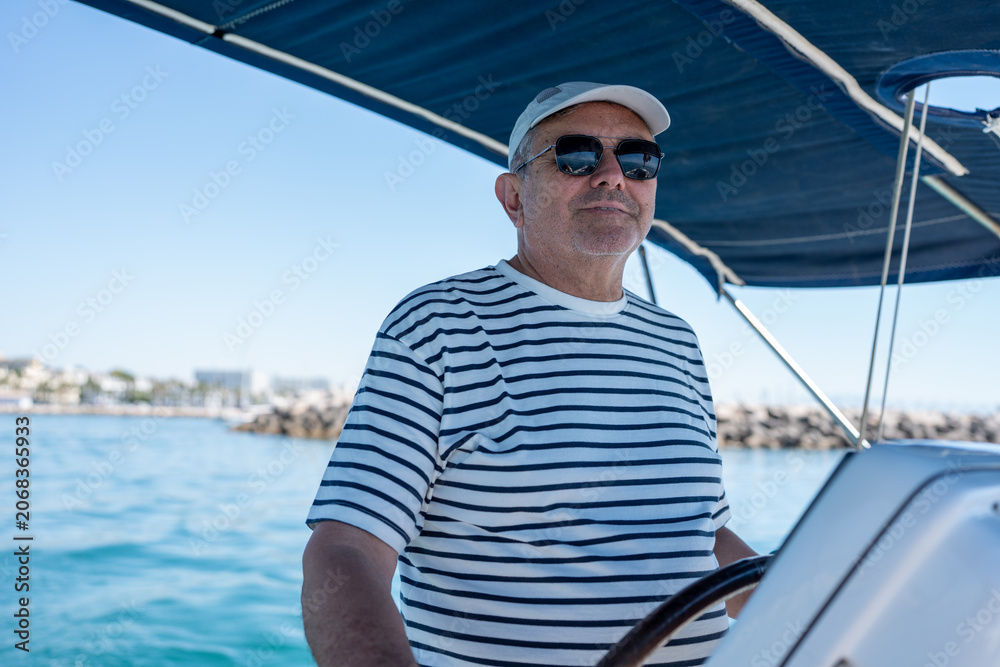 Fototapeta premium Senior man steering sailing boat enjoying summer vacation