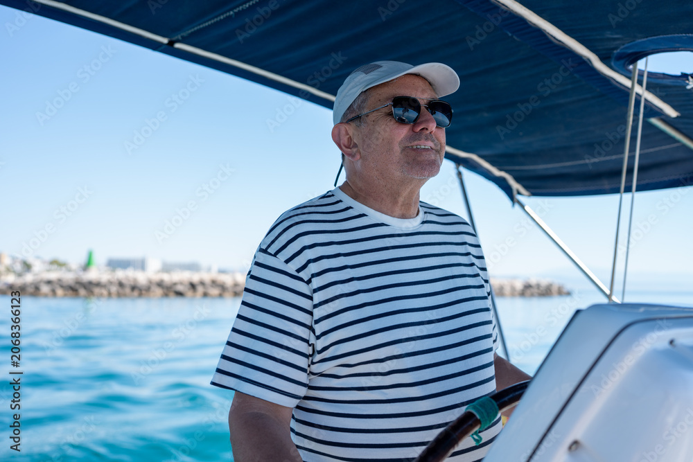 Fototapeta premium Senior man steering sailboat enjoying summer vacation