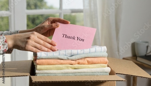 Hands place a thank you card on a neat stack of folded colored textiles inside a box