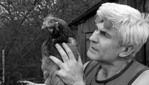 Bild auf Leinwand male farmer holding a brown chicken in his hands