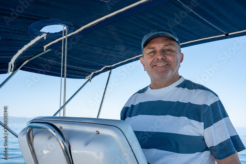 фотографія Cheerful man navigatingsailboat on calm blue sea