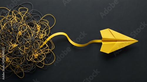 Simplifying complexity concept with untangled yellow paper airplane.