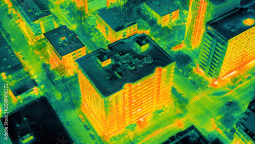 Aerial thermal infrared scan of urban city block showing building heat loss signatures with green yellow orange spectrum contrast for energy audit