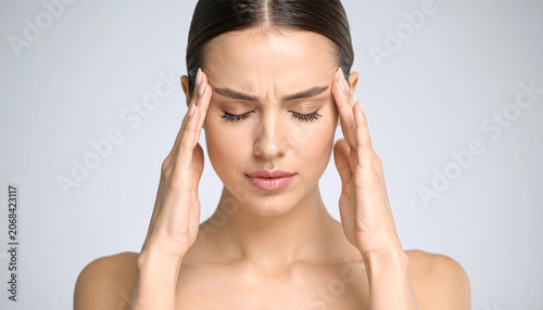 Young Asian woman holding her temples with severe headache or migraine pain, medical concept