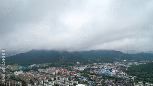 Aerial View of City Neighborhood Below Cloud Covered Green Mountains