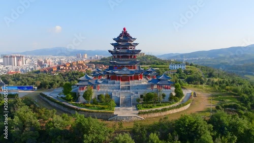 Aerial view of traditional Chinese pagoda on a green hill with mountains