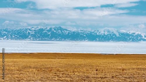 Dry Grassland and Calm Lake with Snow Covered Mountain Range