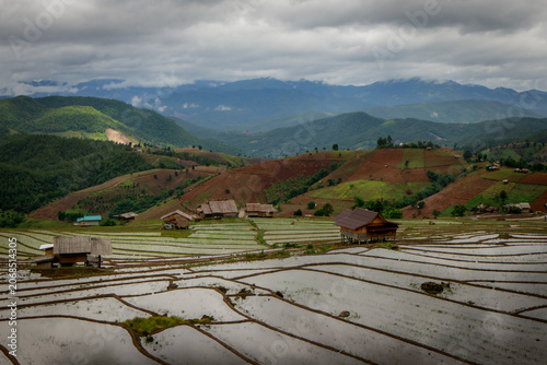 Peaceful rice terraces beneath a striking cloudy sky in a picturesque mountainous setting