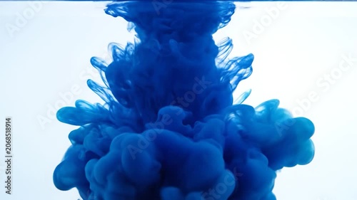 Blue ink cloud swirls in clear water against white background