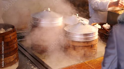 Steaming wooden dumpling steamers in a busy kitchen
