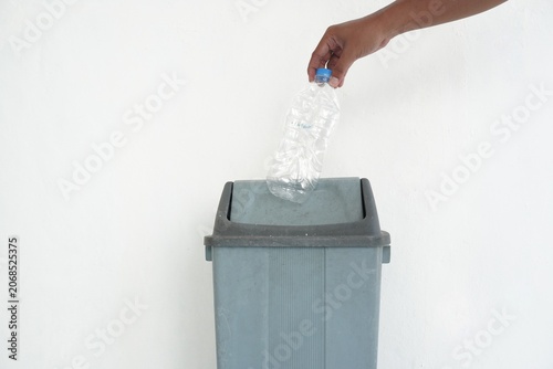 Quadro su tela Close-up of a hand throwing a used bottle into a trash can