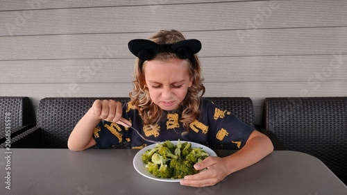 Child Eating Cauliflower with Reluctant Expression