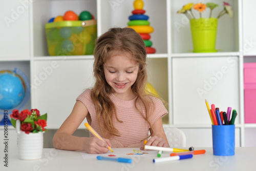 cute girl in the nursery draws at the table