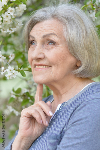 Close-up portrait of smiling elderly woman posing in summer park