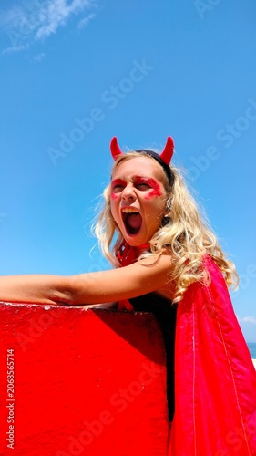 Boy in Devil Costume Shouting Against Blue Sky