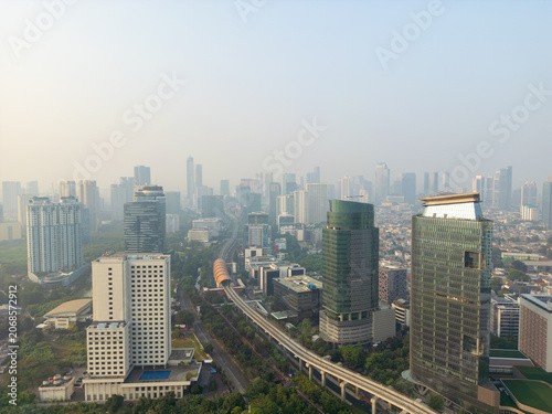 Aerial View of Modern Cityscape with Skyscrapers and LRT Train Track Infrastructure in Morning Haze