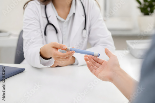 Clinician handing injection pen to patient in consultation