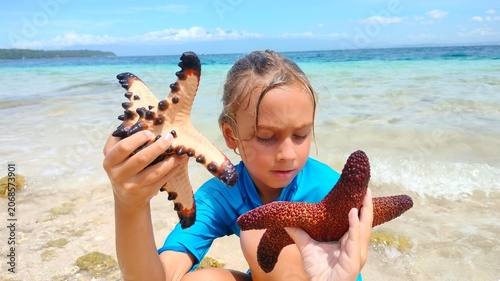 Boy Holding Two Starfish in Sea Water