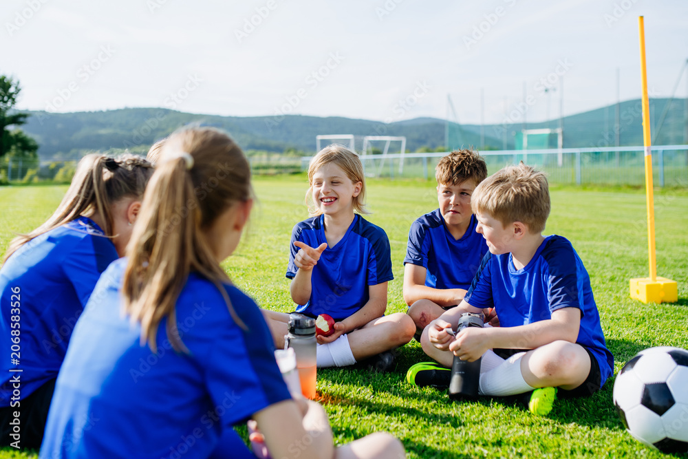 Naklejka premium Children relaxing together after youth football training and exercise.