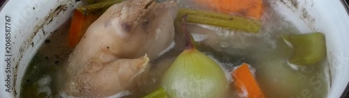 Preparing homemade pork soup stock with chicken onion carrot and celery Simmering food in a cooking vessel.