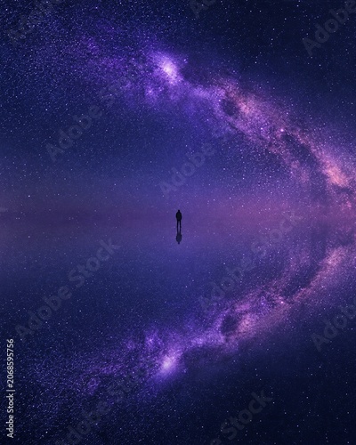 Silhouette of a person standing on a reflective surface under a starry night sky