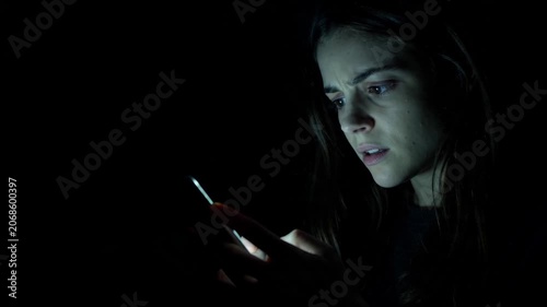 Young woman looking at smartphone screen with worried facial expression