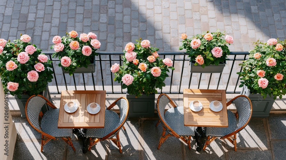Fototapeta premium Aerial view of a parisian cafe terrace with pink roses and coffee cups