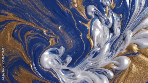 A captivating abstract image showcases swirling patterns of deep blue and shimmering gold, punctuated by a burst of ethereal white smoke, creating a dynamic and visually striking composition.