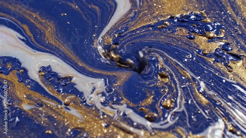 A close-up shot showcases a mesmerizing abstract painting with swirling patterns of deep blue, shimmering gold, and elegant white, creating a luxurious and dynamic visual effect.
