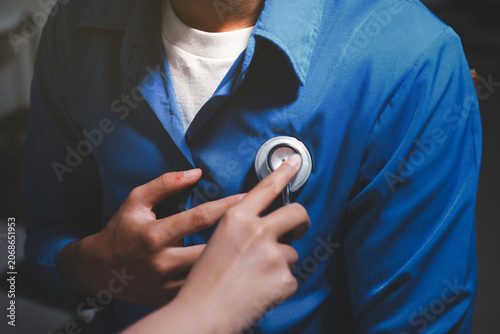 Doctor use stethoscope, checking up heart beat, auscultation in doctor office at hospital. Patient worker has to get medical checkup every year for her health or