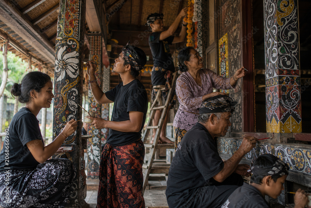 Obraz premium Artisans paint intricate patterns on traditional wooden pillars