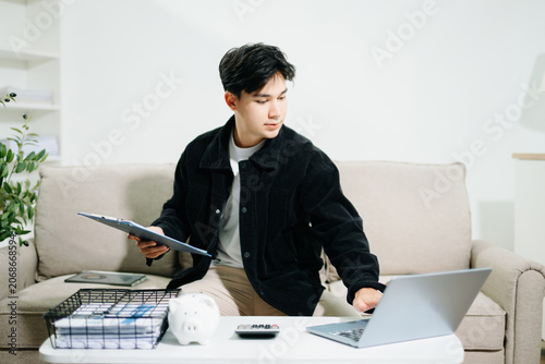 Young man using a tablet for budgeting and financial planning at home. Savings, fintech, money management, investment goals and digital finance concept.