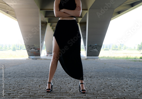 Canvastavla Frau im schwarzen Kleid unter einer modernen Brücke