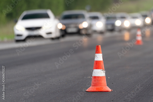 Traffic cones on road with blurred cars and headlights, road work, lane closure, traffic restriction, traffic delay and driver warning