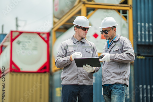 Logistics supervisors review shipment documentation and cargo verification records at container terminal, supporting freight transportation planning and supply chain management operations.