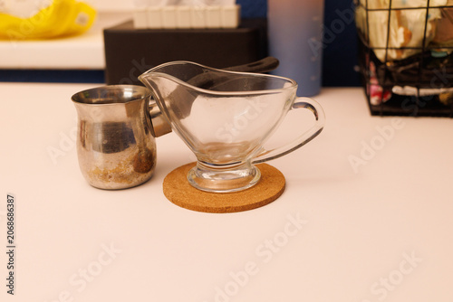 Two containers sit on a cork mat on a kitchen counter. One is clear glass and the other is metal