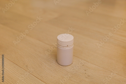 A small container sits on a wooden floor in a well-lit indoor area