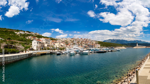 Waterfront promenade of the exclusive Lustica Bay resort showcasing luxury yachts moored along upscale stone residences. Montenegro