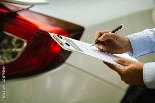Quadro su tela Close-up of an insurance agent inspecting a car and holding a car insurance document during a vehicle assessment, representing auto insurance claims, inspection, and customer service