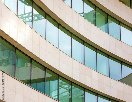 A striking architectural detail showcases a modern building's curved facade and expansive windows, creating a visually dynamic and geometric composition.