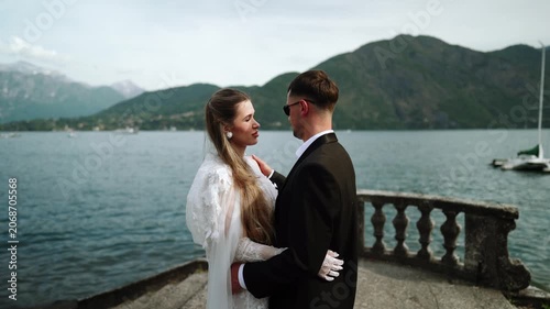 Romantic wedding couple embraces by Lake Como mountains