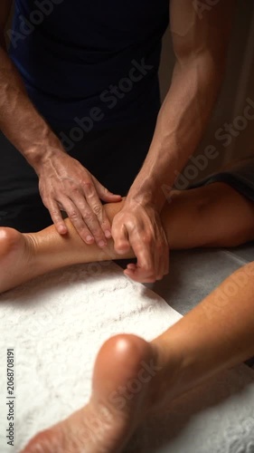Male therapist massaging a woman's calf muscle with oil in a spa for physical therapy and wellness
