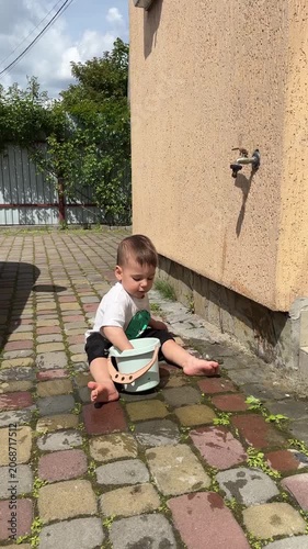 Toddler playing with bucket in sunny yard