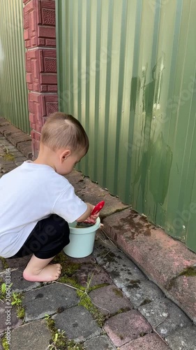 Young child painting a green gate outdoors