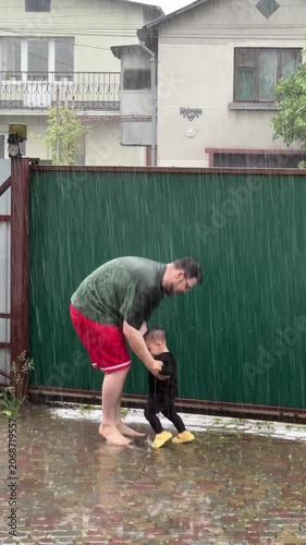 Man lifting child in the rain in backyard