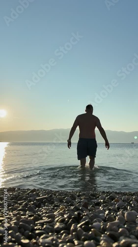Calm sea sunset with rocky shore and swimmer