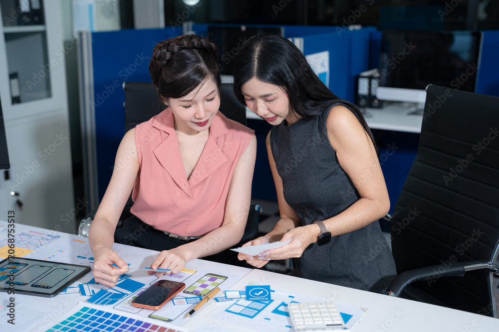 Fototapeta premium Creative team brainstorming digital marketing strategy, two asian woman discussing branding and online business growth.